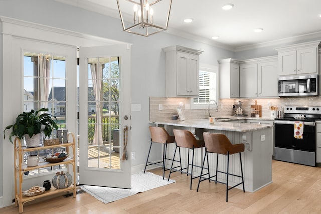 kitchen featuring sink, white cabinets, light stone countertops, ornamental molding, and stainless steel appliances