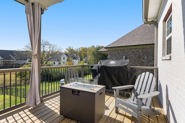 wooden terrace featuring a fire pit and a grill