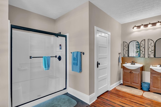 bathroom with vanity, a textured ceiling, an enclosed shower, and wood-type flooring