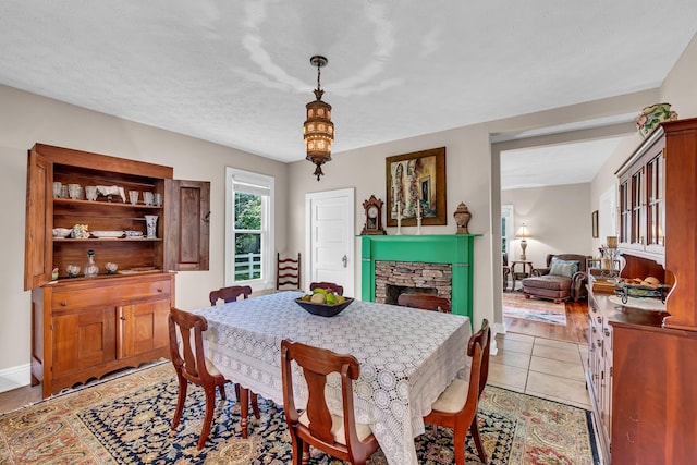 tiled dining space featuring a textured ceiling and a fireplace