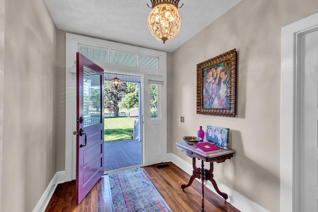 foyer entrance featuring hardwood / wood-style flooring, a textured ceiling, and a chandelier