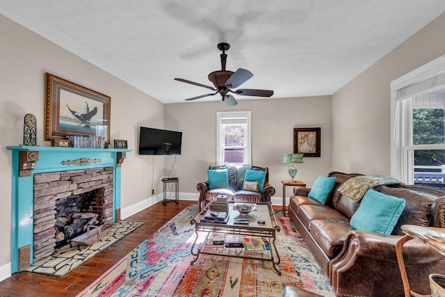 living room with a fireplace, a healthy amount of sunlight, dark wood-type flooring, and ceiling fan