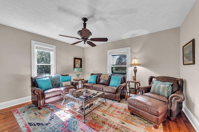 living room with hardwood / wood-style flooring, ceiling fan, and a textured ceiling