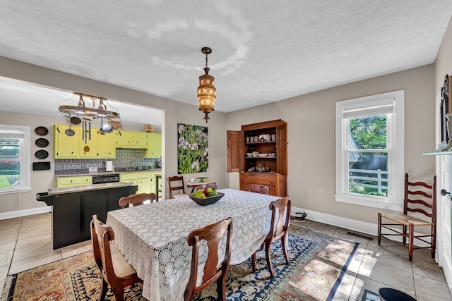 dining room featuring sink, light tile patterned floors, and a textured ceiling