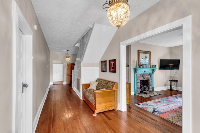 corridor featuring hardwood / wood-style flooring, a textured ceiling, and an inviting chandelier