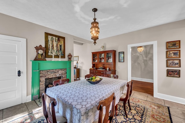 tiled dining area featuring a stone fireplace