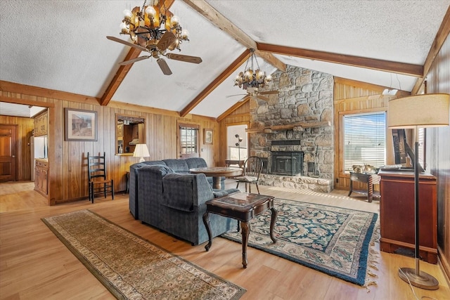 living room with plenty of natural light, lofted ceiling with beams, light hardwood / wood-style flooring, and a stone fireplace