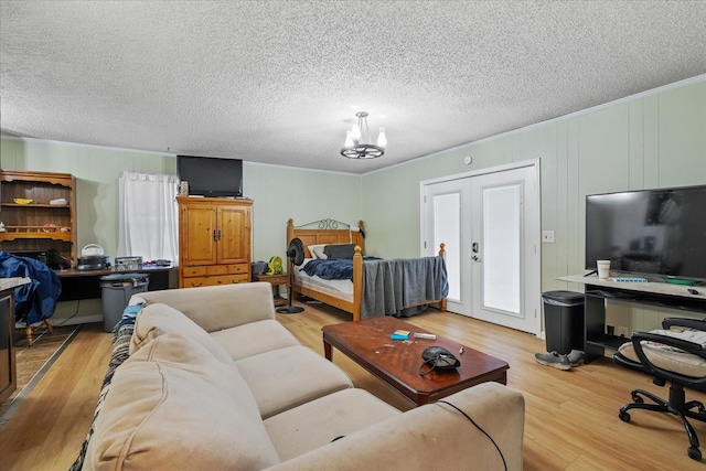 bedroom with hardwood / wood-style floors, an inviting chandelier, a textured ceiling, and french doors