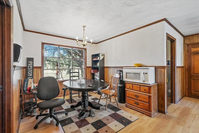 home office with an inviting chandelier, light hardwood / wood-style flooring, and ornamental molding