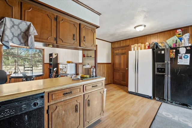 kitchen featuring crown molding, black appliances, wooden walls, and light hardwood / wood-style floors