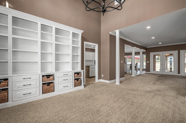 unfurnished living room with ornamental molding, french doors, carpet, and ornate columns