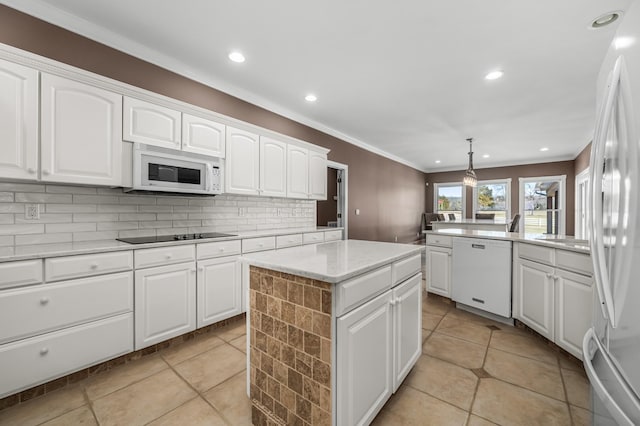 kitchen featuring white appliances, white cabinets, a center island, and hanging light fixtures