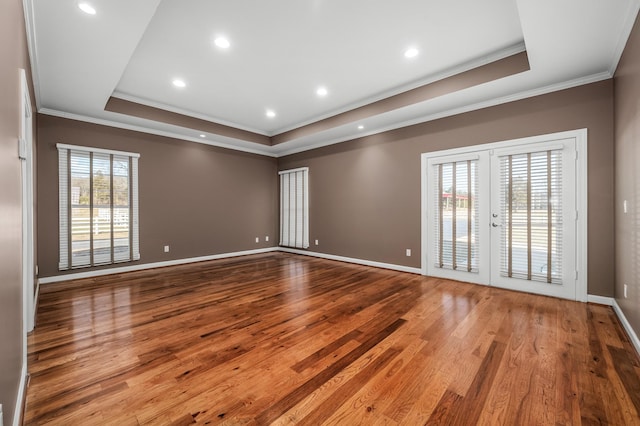 unfurnished room with plenty of natural light, light hardwood / wood-style flooring, and a raised ceiling