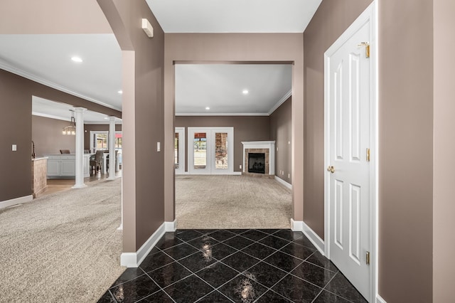 hallway featuring decorative columns, ornamental molding, and dark colored carpet