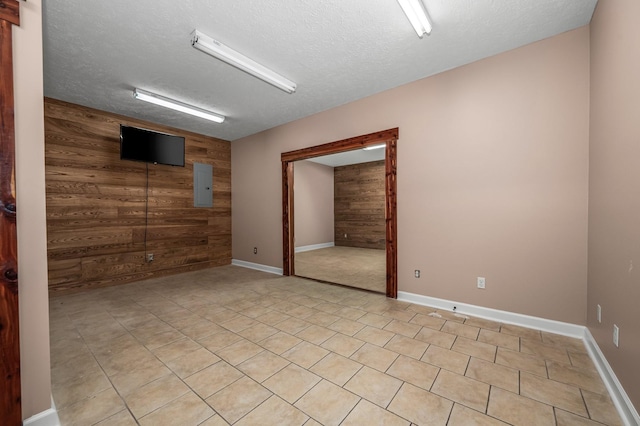 unfurnished room featuring electric panel, wooden walls, and a textured ceiling