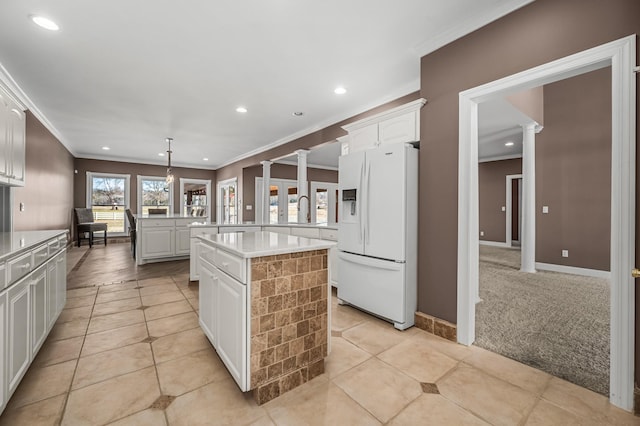 kitchen featuring white cabinets, a center island, decorative light fixtures, white refrigerator with ice dispenser, and decorative columns