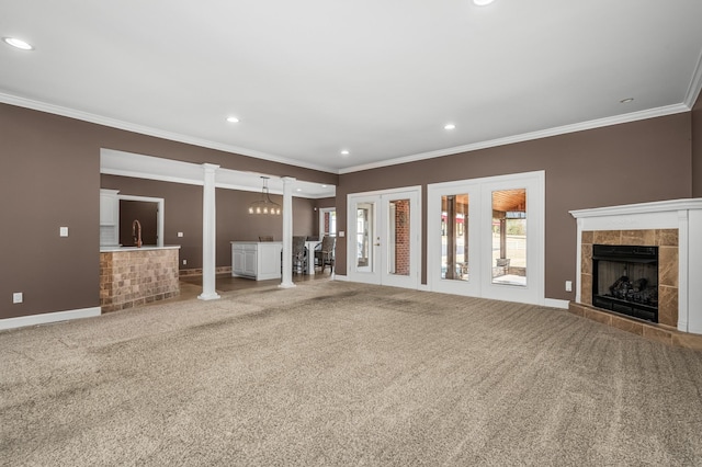 unfurnished living room featuring decorative columns, carpet flooring, ornamental molding, and a tile fireplace