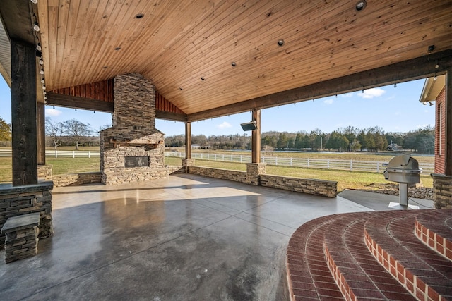 view of patio with a rural view and an outdoor stone fireplace