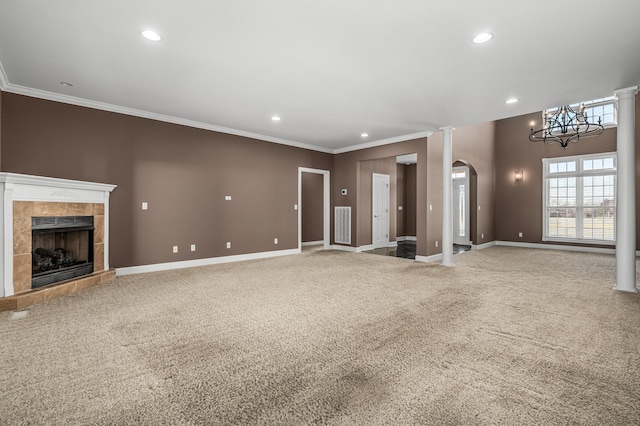 unfurnished living room with carpet flooring, ornate columns, ornamental molding, an inviting chandelier, and a tiled fireplace