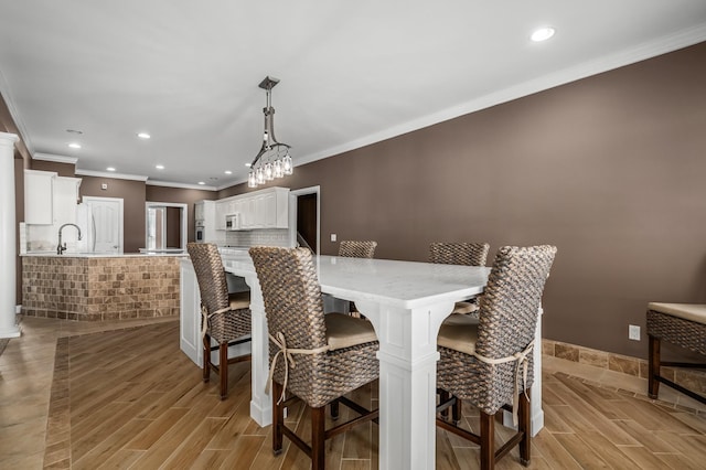 dining area featuring sink, light hardwood / wood-style flooring, and ornamental molding