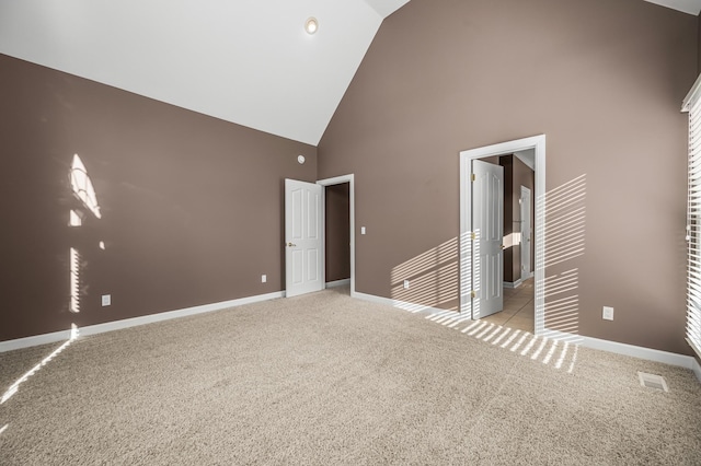 unfurnished bedroom with high vaulted ceiling and light carpet