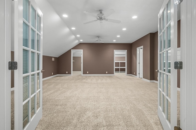 spare room with vaulted ceiling, french doors, ceiling fan, and light colored carpet