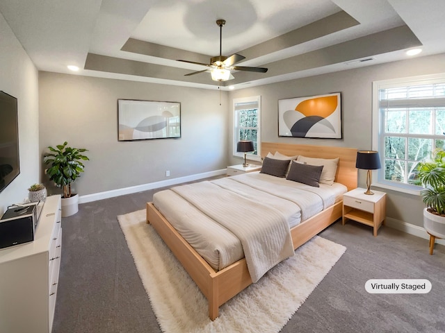 carpeted bedroom featuring ceiling fan and a tray ceiling