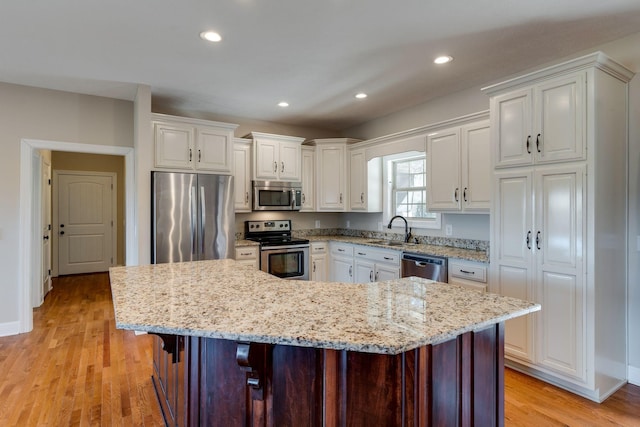 kitchen with white cabinetry, appliances with stainless steel finishes, a center island, and a kitchen breakfast bar