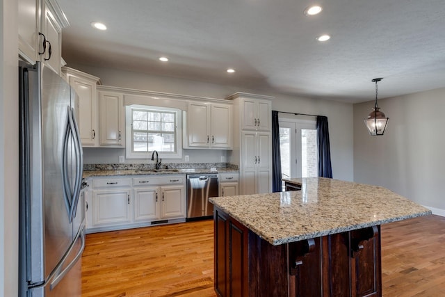 kitchen with sink, white cabinetry, hanging light fixtures, a kitchen island, and stainless steel appliances