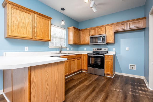 kitchen with kitchen peninsula, dark hardwood / wood-style flooring, decorative light fixtures, sink, and appliances with stainless steel finishes