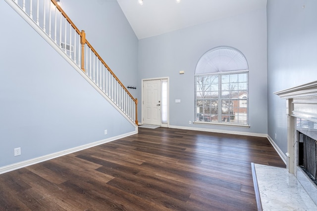 unfurnished living room featuring high vaulted ceiling, dark wood-type flooring, and a premium fireplace