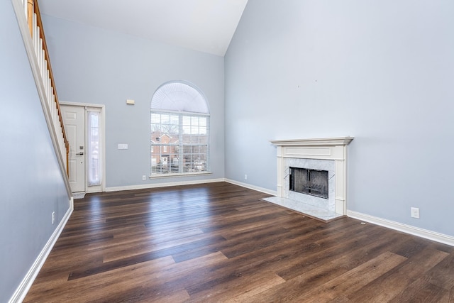 unfurnished living room with high vaulted ceiling, a high end fireplace, and dark hardwood / wood-style floors