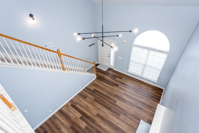 staircase with a notable chandelier, hardwood / wood-style flooring, and a high ceiling