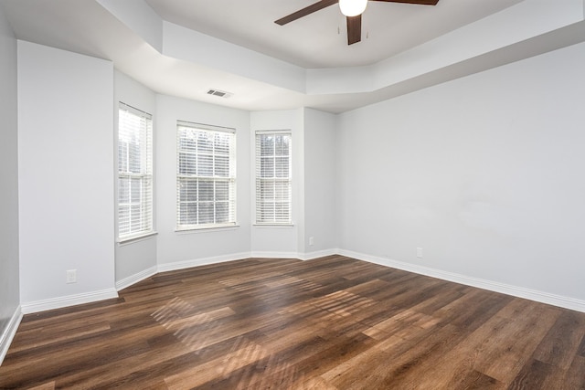 empty room featuring ceiling fan, dark hardwood / wood-style floors, and a tray ceiling