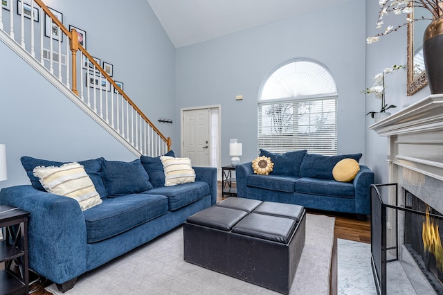 living room featuring high vaulted ceiling, a tile fireplace, and hardwood / wood-style floors