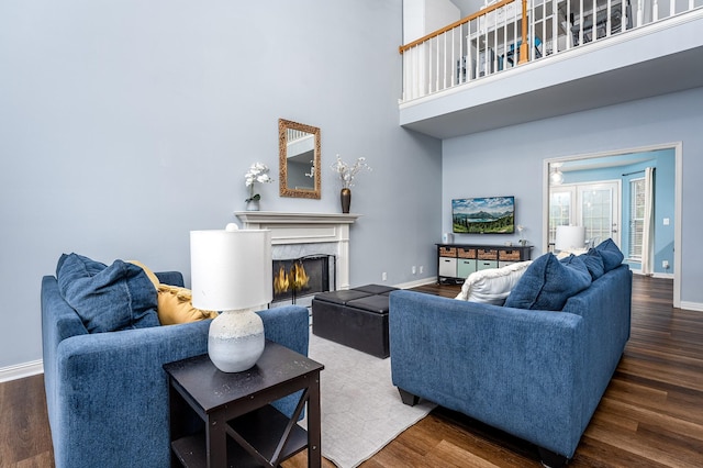 living room featuring dark hardwood / wood-style floors, a towering ceiling, and a high end fireplace