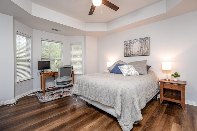 bedroom featuring ceiling fan, dark hardwood / wood-style floors, and a tray ceiling