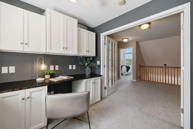 interior space with white cabinetry, vaulted ceiling, ceiling fan, and dark stone countertops