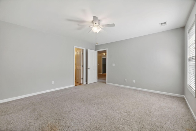 carpeted empty room with ceiling fan and a wealth of natural light