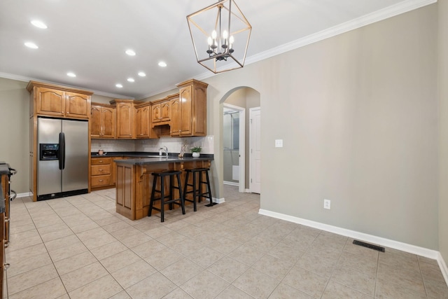 kitchen featuring a kitchen breakfast bar, crown molding, stainless steel fridge with ice dispenser, a center island, and decorative backsplash