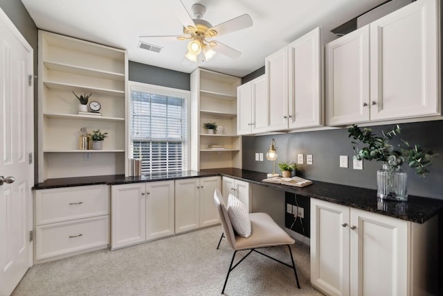 office space featuring ceiling fan, light carpet, and built in desk