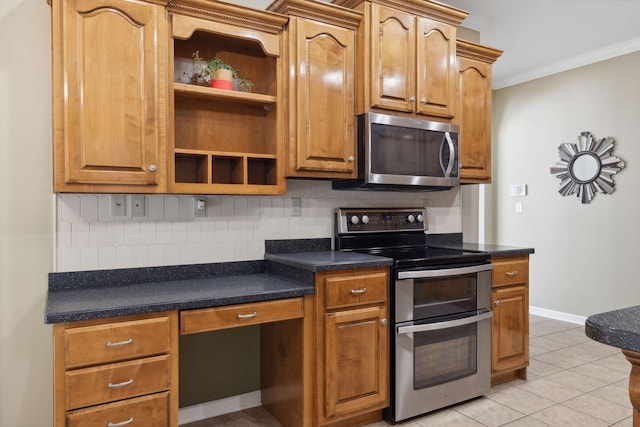 kitchen featuring appliances with stainless steel finishes, built in desk, tasteful backsplash, light tile patterned flooring, and crown molding