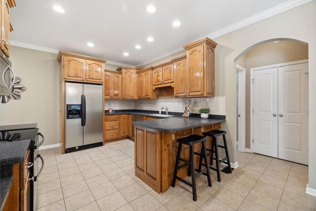 kitchen with a kitchen breakfast bar, sink, ornamental molding, decorative backsplash, and stainless steel appliances