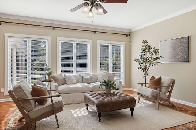 living room featuring ceiling fan, a wealth of natural light, ornamental molding, and light wood-type flooring