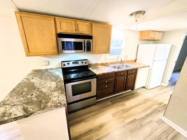 kitchen with sink, light wood-type flooring, light stone countertops, and appliances with stainless steel finishes