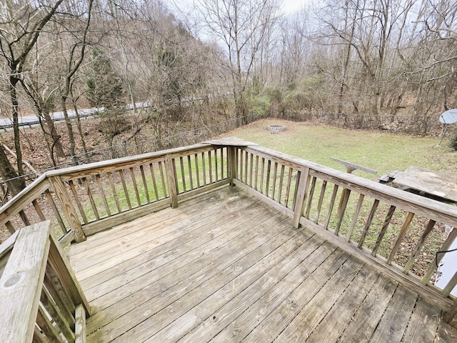 wooden deck with an outdoor fire pit and a yard