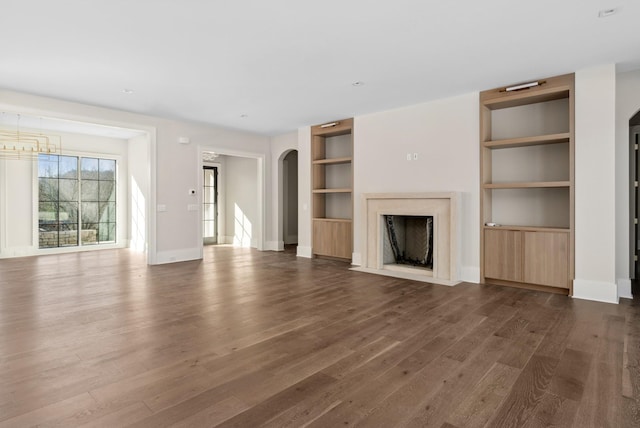 unfurnished living room with built in shelves, dark hardwood / wood-style floors, and a fireplace