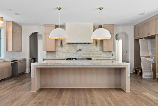 kitchen featuring tasteful backsplash, light brown cabinetry, dishwasher, and hanging light fixtures