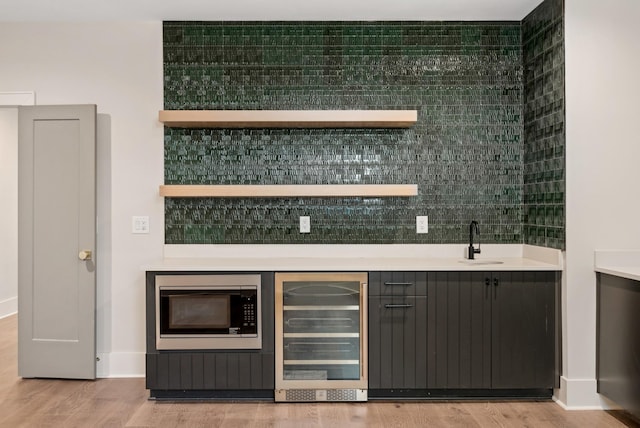 bar with sink, light hardwood / wood-style flooring, wine cooler, and built in microwave