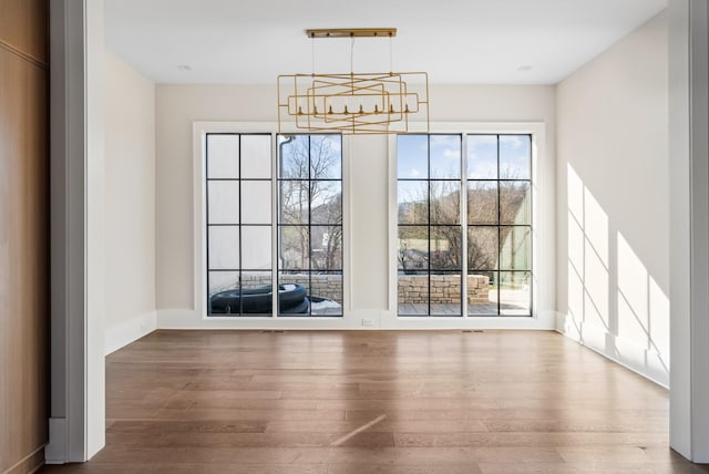 unfurnished dining area with hardwood / wood-style flooring and an inviting chandelier